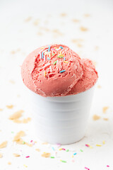 Top view of strawberry ice cream in white bowl on white table with wafer crumbs, selective focus, vertical, with copy space
