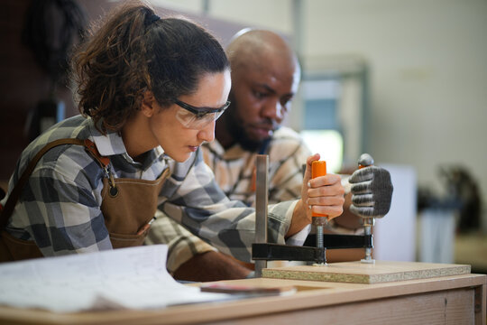 Young female capenter in apron working in carpentry woodworking workshop, Carpenter woman concept.