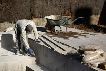 Obrero trabajando en obra de construcción de una piscina en un chalet.	