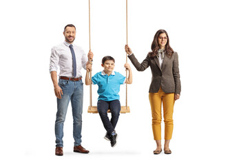 Parents standing next to a boy on a wooden swing