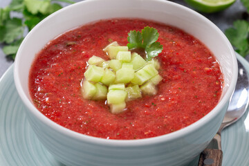 Gazpacho soup garnished with cucumber and cilantro, in bowl, horizontal closeup