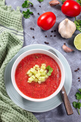 Cold soup Gazpacho garnished with cucumber and cilantro, in bowl, vertical top view