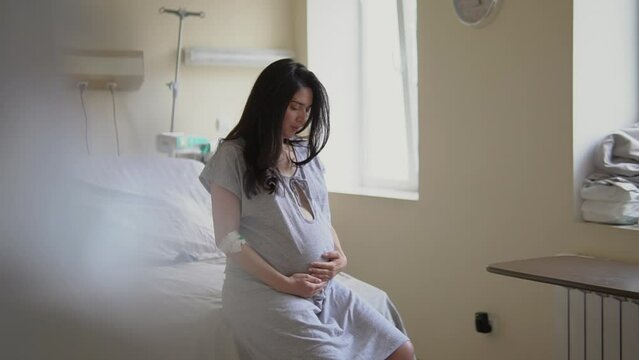 Brunette woman waits for labor to begin in hospital ward