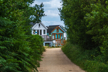 Hengistbury Head, UK - July 1st 2023: A tree lined road leading to beach huts on Mudeford Sandbank.