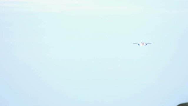 Front view of passenger plane descending before landing. Aircraft fliea in the blue sky, long shot. Tourism and travel concept, air flight