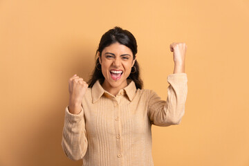 excited young woman raising arms and celebrating in studio shot. celebration, positive, success...