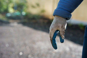 Hand in dirty gardening gloves after planting plants in the garden