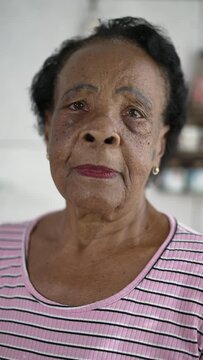 Portrait of a senior black Brazilian woman looking at camera with neutral expression. African American elderly lady in 70s with serious face close-up in vertical video