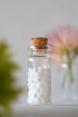 Alternative medicine with white homeopathic granules and natural plants in the background