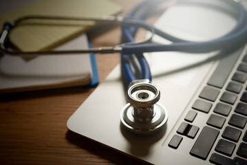 Stethoscope on laptop keyboard, telehealth concept