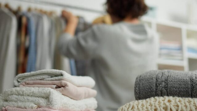 Seasonal clothes, Stylish fashionista Responsibly Chooses hanging clothes on a hanger. Dressing room with daily use items, Concept Pretty woman Looking at shirt indoors, shopping mall
