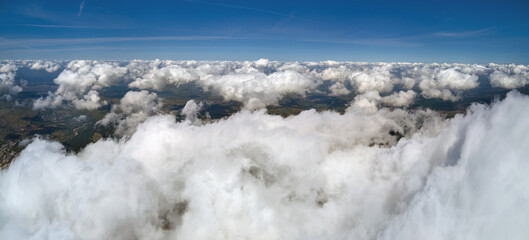 Aerial view from airplane window at high altitude of earth covered with white puffy cumulus clouds