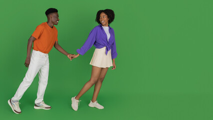 Smiling young african american woman in casual hold boyfriend hand, leads