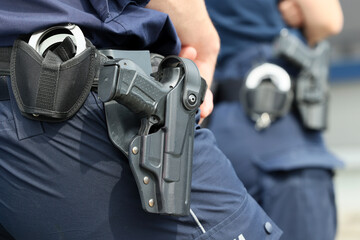  Kajdanki i pistolet w pokrowcu na pasie policjanta.  - obrazy, fototapety, plakaty