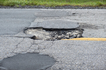 Damaged asphalt road with deep pothole on american highway surface. Ruined roadway in urgent need...