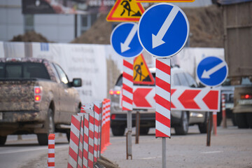 Roadworks warning traffic signs of construction work on city street and slowly moving cars
