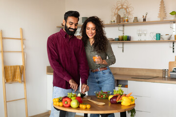 Loving middle eastern man husband cooking dinner for his beautiful wife, spouses having conversation in kitchen