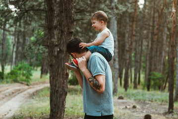 father's day. Happy European-looking father walks with his young cute two-year-old son on his...