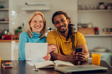 A happy couple planning together a home budget while sitting at home and smiling at the camera.