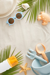 Fototapeta na wymiar Children's summer fun by the sea concept. Top view vertical flat lay of beach toys, sunscreen spray, eyeglasses, palm leaves, sun hat, starfish, seashell on sand background with space for ad or text