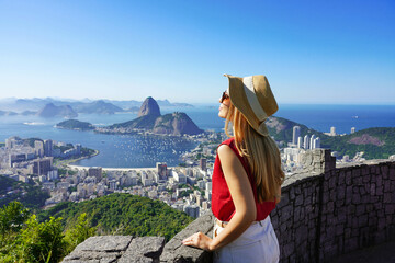 Fashion tourist woman on terrace in Rio de Janeiro with the famous Guanabara bay and the cityscape of Rio de Janerio, Brazil