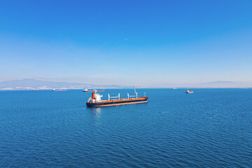 Bulk carrier ships stay at the anchor on anchorage near industrial port, aerial view