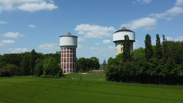 A smooth span overlooking two water towers, against a backdrop of green, cultivated fields, and trees. Water towers in Hamm, Germany.
