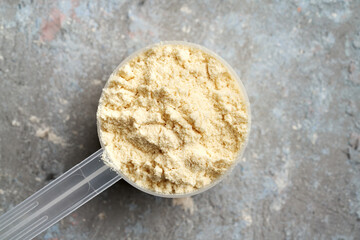 Whey protein powder in a plastic measuring spoon, top view