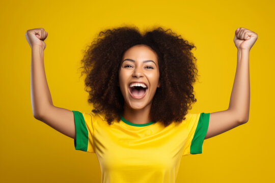 smiling Brazilian fan woman celebrating in front of a gray background. she is dressed in vibrant clothing adorned with national motifs and symbols of Brazil