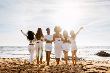 Bride's team. Back view of group of young diverse women posing and embracing by the seashore. Hen party celebration - Powered by Adobe