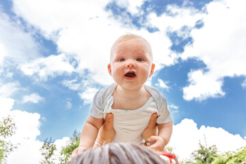 Happy family outdoor. Mother hands lifting in air little toddler baby. Mom holding embracing her...