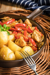 Fried pieces of chicken with red peppers and onions.