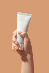 Cosmetic mask or cleansing foam in woman hand on peach beige background