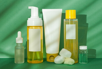 Cosmetic yellow and white cleansing set on green background with palm leaf shadow