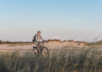 young woman on a bicycle rides along the beach in Sankt Peter-Ording