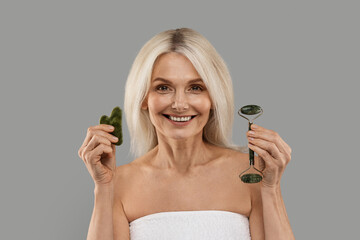Beauty Tools. Mature woman holding jade guasha stone scraper and greenstone roller