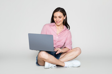 Naklejka premium Happy pretty young woman using laptop, pastel background