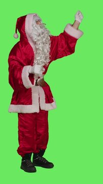 Vertical video Side view of santa choirmaster conducting band, conductor in winter seasonal costume accompany choir over full body greenscreen backdrop. Character pretends to be musical director