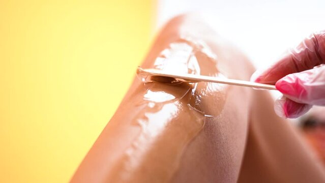 Cosmetologist applies ultrasound laser hair removal gel to girl's leg for depilation close-up
