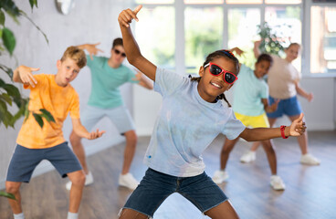 Obraz premium Positive boy exercising in group of classmates during dance class at school