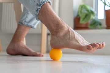 Man using silicone ball for foot massage doing prevention physical exercise for improving blood...