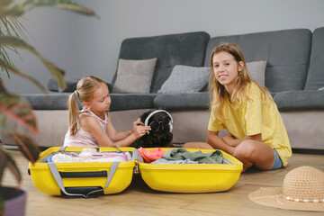 Children packing suitcase for travel and play with a dog. Sisters having fun with pet while getting ready for a trip. Dog in sunglasses and sunhat. going on vacation