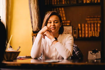 Attractive young brunette woman sitting at a table in the library.