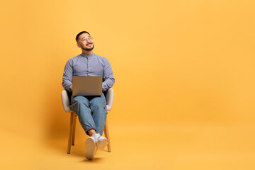 Asian Man With Laptop Sitting In Chair And Looking At Copy Space
