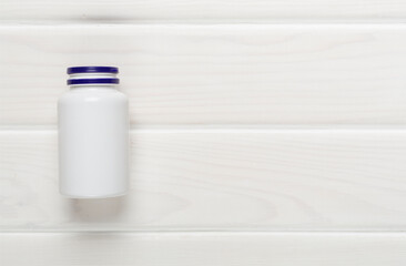 Plastic bottle with vitamins on wooden background, top view