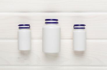 Plastic bottles with vitamins on wooden background, top view