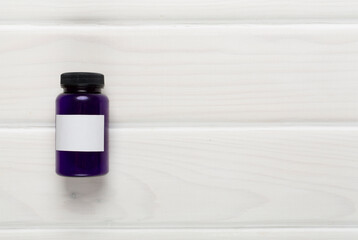 Plastic bottle with vitamins on wooden background, top view