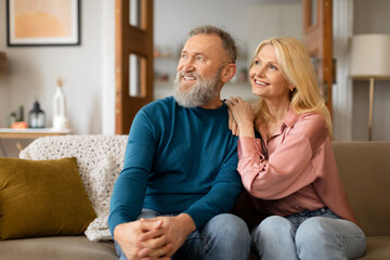 Mature Couple Enjoying Domestic Comfort Embracing On Sofa At Home