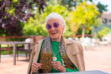 An elderly woman dancing in the garden of a nursing home or retirement home at a summer party wearing sunglasses - obrazy, fototapety, plakaty