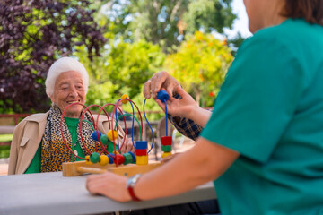 Hands of two elderly people in the garden of a nursing home or retirement home playing with games...